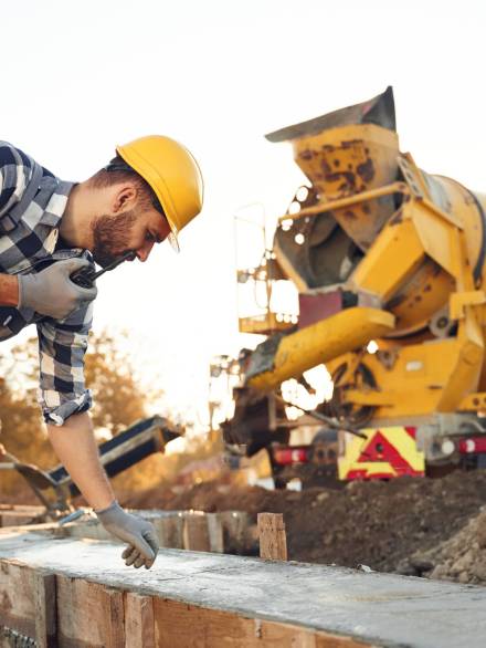 Concrete on the foundation of the house. Worker is on the construction site at daytime.