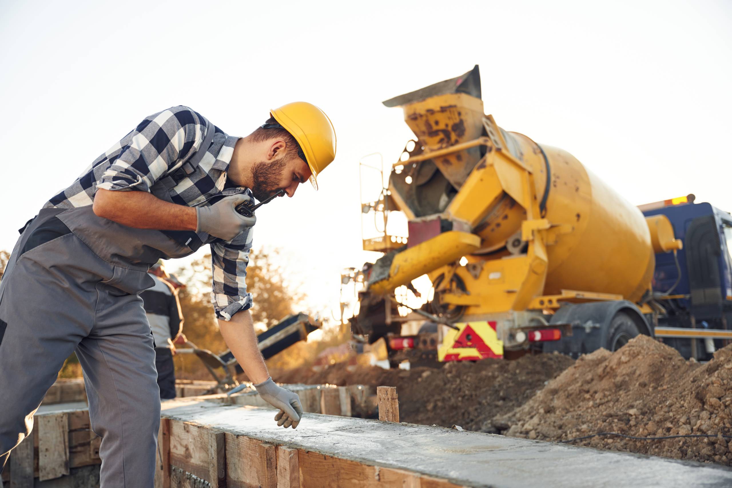 Concrete on the foundation of the house. Worker is on the construction site at daytime.